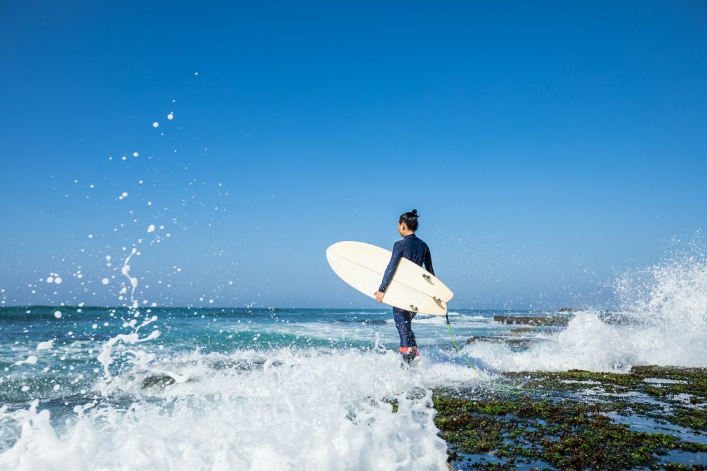 Surfer with surfboard at seaside